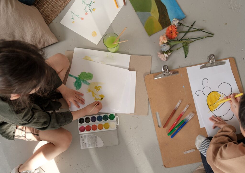 Niños pintando sobre hojas de papel con pintura